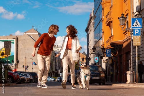Young Caucasian couple with pet walking to the city. Training purebreed aussie dog