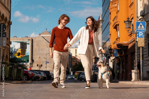 Quadro em tela Happy young Caucasian couple with pet walking at city