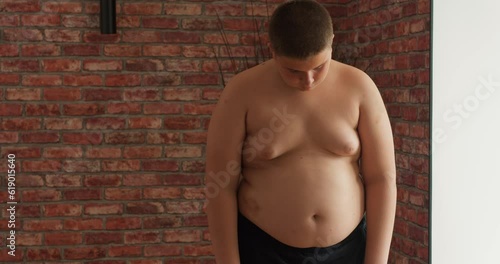 Upset plump shirtless boy after weighing. Teenage kid need to lose some excess weight. teen has problems with weight Slow motion depression kid cannot stop eating fast food and go in for sport illness