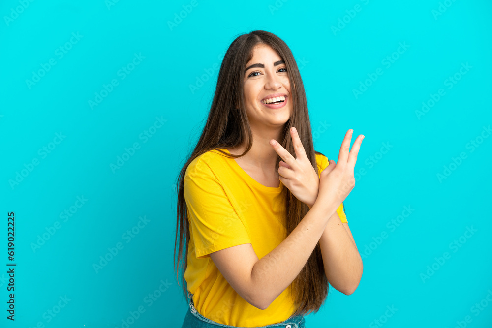 Young caucasian woman isolated on blue background smiling and showing victory sign Young caucasian woman isolated on blue background smiling and showing victory sign