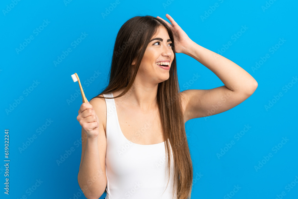 Young caucasian woman brushing teeth isolated on blue background smiling a lot Young caucasian woman brushing teeth isolated on blue background smiling a lot