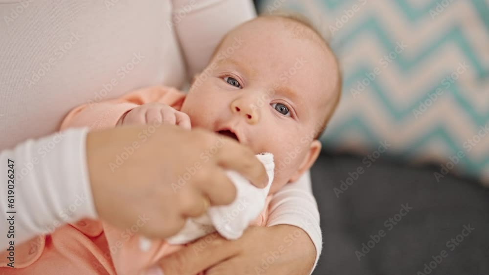 Mother and daughter sitting on sofa cleaning mouth at home Mother and daughter sitting on sofa cleaning mouth at home