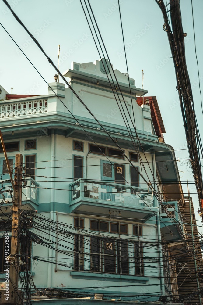 Majestic white and blue building near intertwining electric cables in Bangkok, Thailand