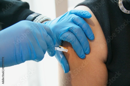 Doctor injecting with hypodermic needle on shoulder
