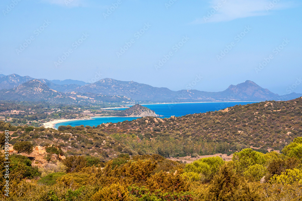 Landscape with a bay with blue sea with mountains in the background in summer on the island of Sardinia in Italy.