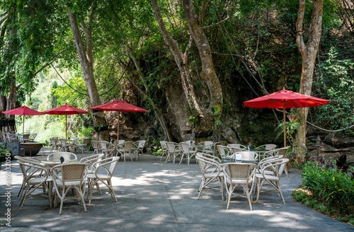 a bunch of tables and chairs in the shade at an outdoor cafe