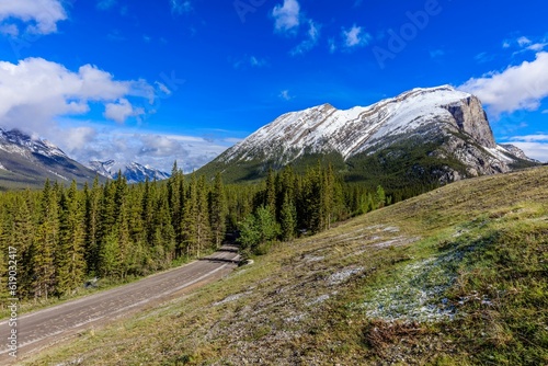 Expansive view of a winding highway road that cuts through a snow-covered hillside in Kananaskis