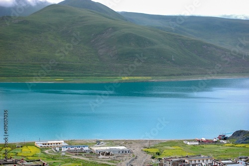 Yamzho Yumco lake against a green mountain on a sunny day photo