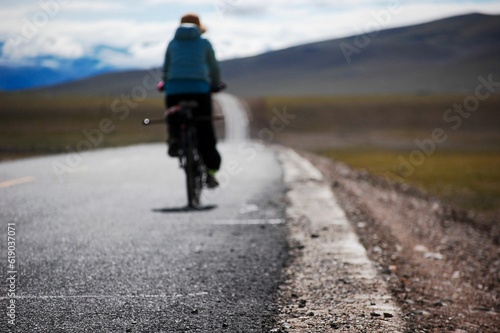 Cyclist riding on a road through fields on a sunny day
