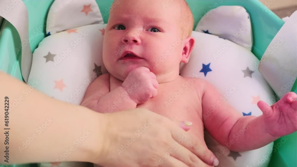 A newborn baby takes a bath. A lovely child is undergoing military