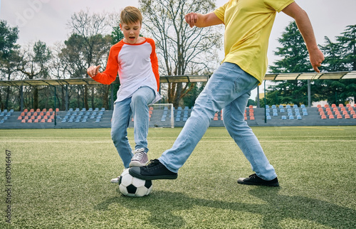 Father and Son play football on stadium outdoors, Happy family bonding, fun, players in soccer in dynamic action playing in sunny day, holidays time. 