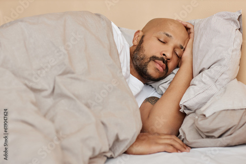 Portrait of adult black man sleeping in comfortable bed in cozy home