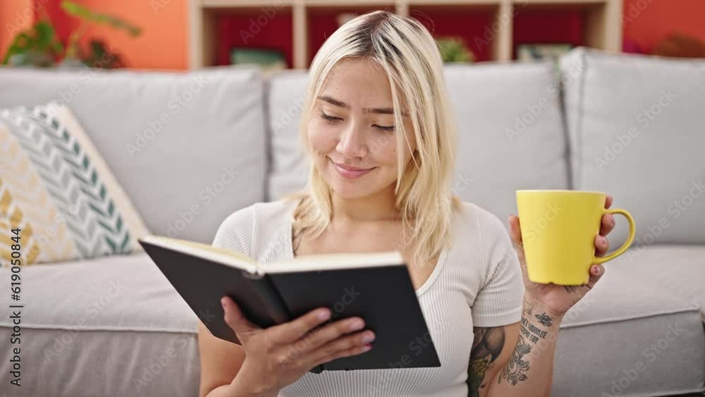 Young beautiful hispanic woman reading book and drinking coffee sitting on floor at home Young beautiful hispanic woman reading book and drinking coffee sitting on floor at home
