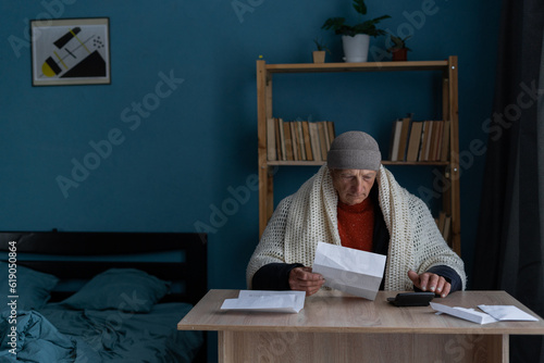 The senior man holding gas and heating bills and calculating costs on calculator. Payment for heating in winter. photo