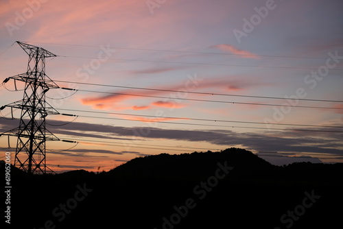 Serene Black Mountain Range at Twilight with Vibrant Orange Sky and Silhouetted Electric Poles