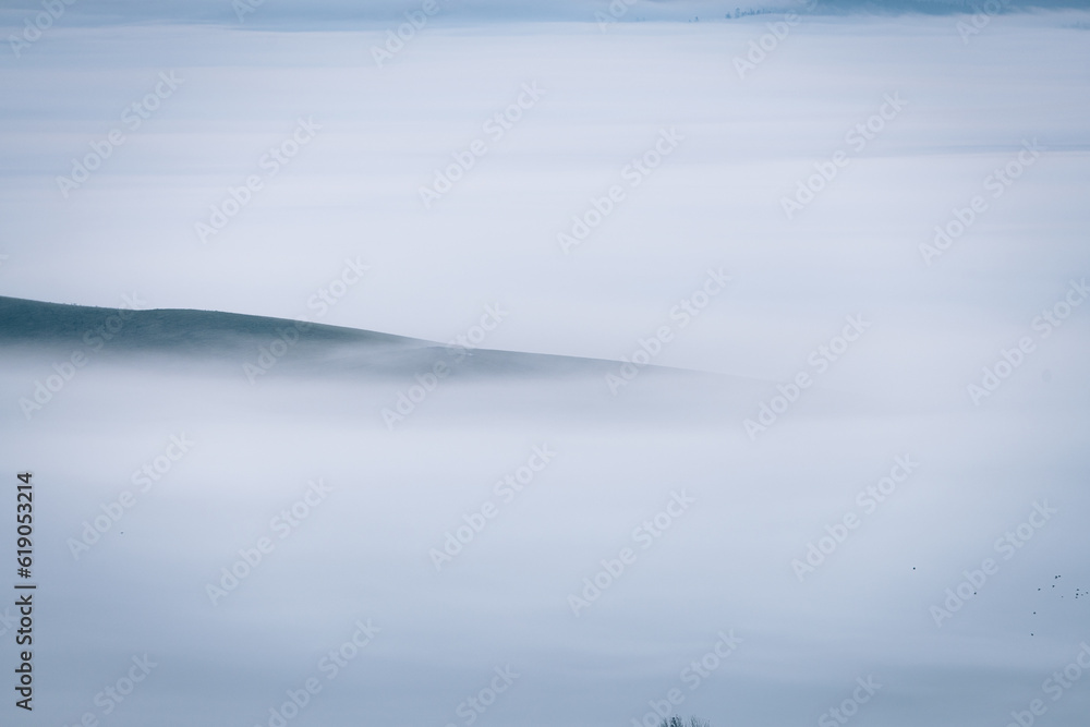 Mountains in a fog illuminated by rising sun. Autumn landscape with vivid sunlight. 