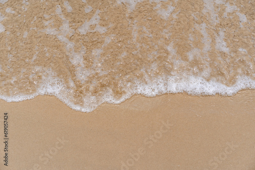 Fototapeta Naklejka Na Ścianę i Meble -  closed up of sea wave with white foam and softness sand background textured on a sunny day, clean and empty beach for outdoor summer activity