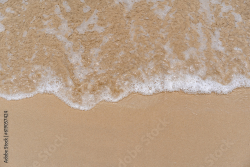 closed up of sea wave with white foam and softness sand background textured on a sunny day, clean and empty beach for outdoor summer activity