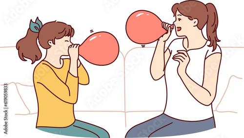 Obraz na plátně Mother and daughter inflate balloons sitting on sofa to decorate apartment for b