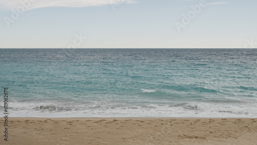 Fototapeta Naklejka Na Ścianę i Meble -  Clear blue waves with strong wind on a sandy empty beach in Cannes in spring