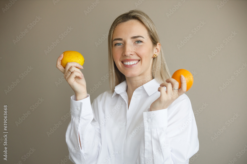 Portrait of a young smiling woman in a white shirt with fruits in her hands in the background Portrait of a young smiling woman in a white shirt with fruits in her hands in the background