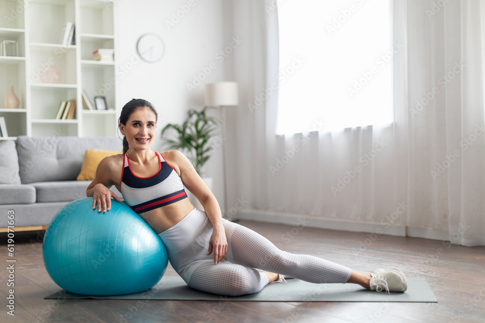 Sporty pretty brunette woman posing with fit ball at home