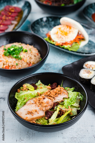 Salad with chicken fillet, rice with chicken and flatbread with bacon and fried egg on a table.