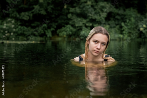 Portrait of a young beautiful blonde girl in the river.