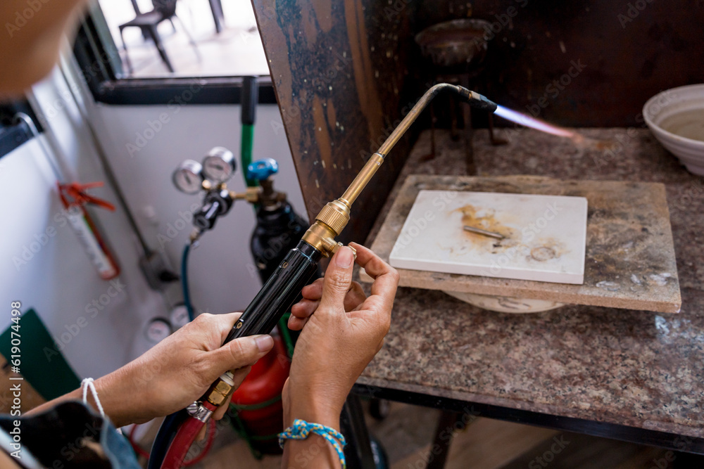 Obraz premium Jeweler using a burner to shape a piece in a workshop