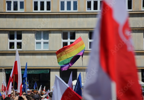 Rainbow flag symbolizing LGBTQ+ groups waves together with flags of Poland and EU during public demonstration to support democracy