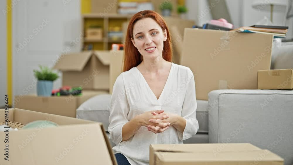 Young redhead woman sitting on floor speaking at new home Young redhead woman sitting on floor speaking at new home