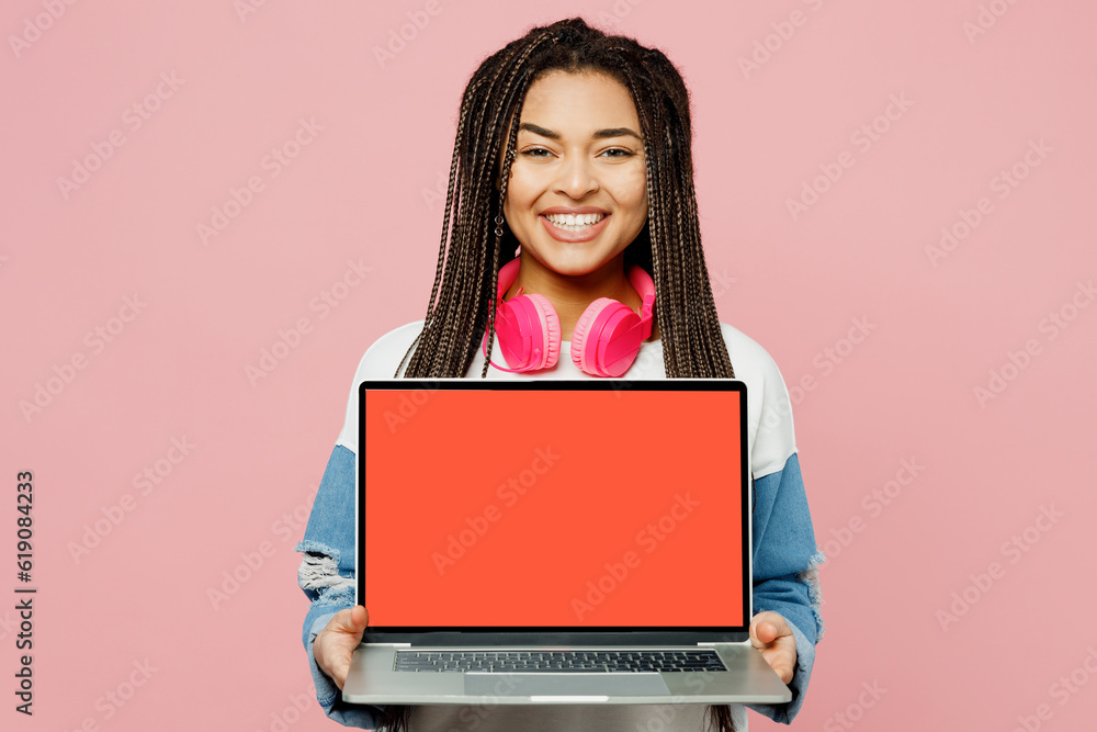 Young IT woman of African American ethnicity wear white sweatshirt casual clothes hold use work on blank screen workspace area laptop pc computer isolated on plain pastel light pink background studio. Young IT woman of African American ethnicity wear white sweatshirt casual clothes hold use work on blank screen workspace area laptop pc computer isolated on plain pastel light pink background studio.