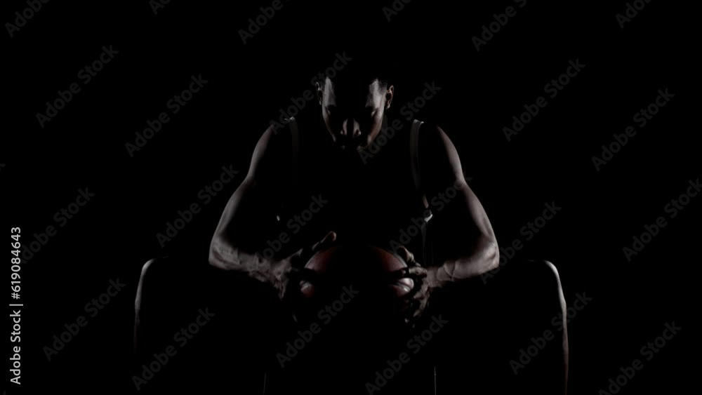 Basketball player sitting on a bench. Concentrated african american sports man against black background. Basketball player sitting on a bench. Concentrated african american sports man against black background.