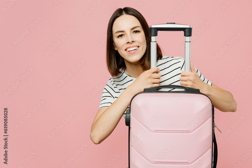 Traveler woman wear casual clothes t-shirt hold suitcase isolated on plain pastel pink color background studio. Tourist travel abroad in free spare time rest getaway. Air flight trip journey concept. Traveler woman wear casual clothes t-shirt hold suitcase isolated on plain pastel pink color background studio. Tourist travel abroad in free spare time rest getaway. Air flight trip journey concept.
