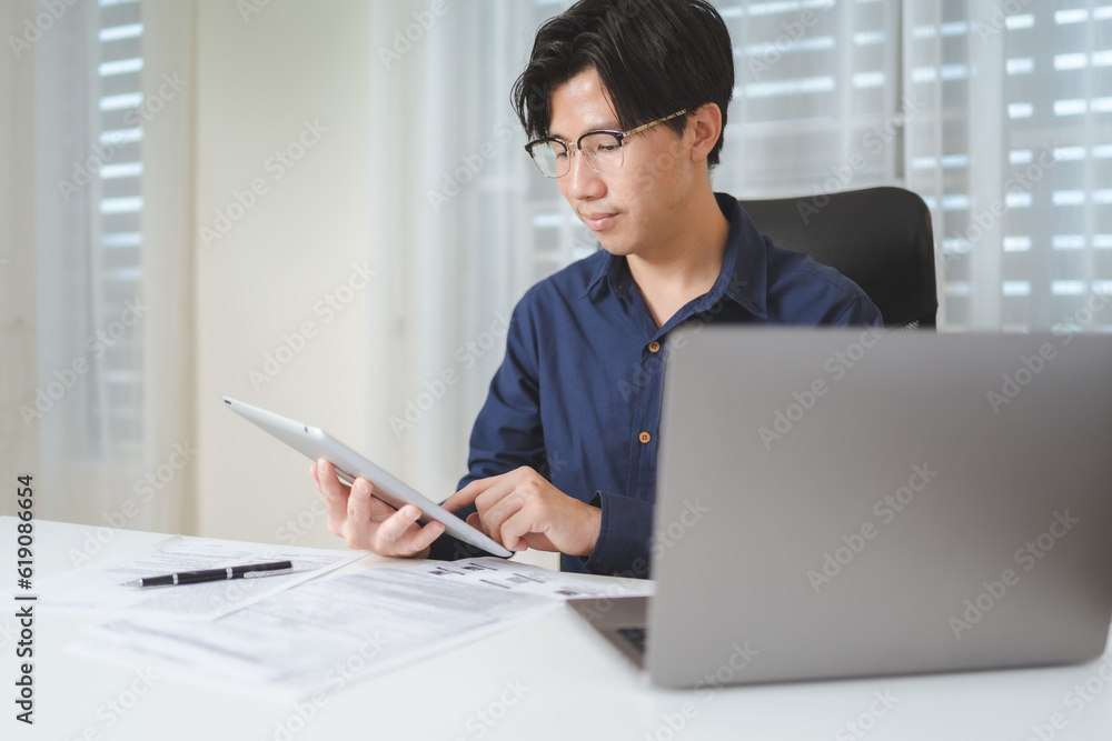Asian Businessman, trader or investor using ,tablet and laptop for trading, investing on stock market or Bitcoin cryptocurrency on online platform. Business man pointing on laptop. Investment concept.