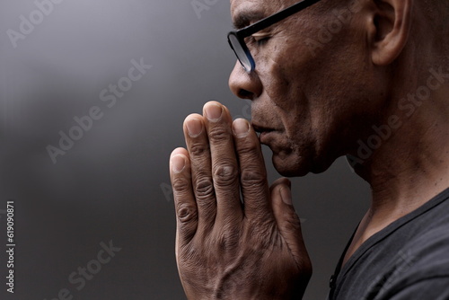 black man praying to god with hands together Caribbean man praying stock photo	