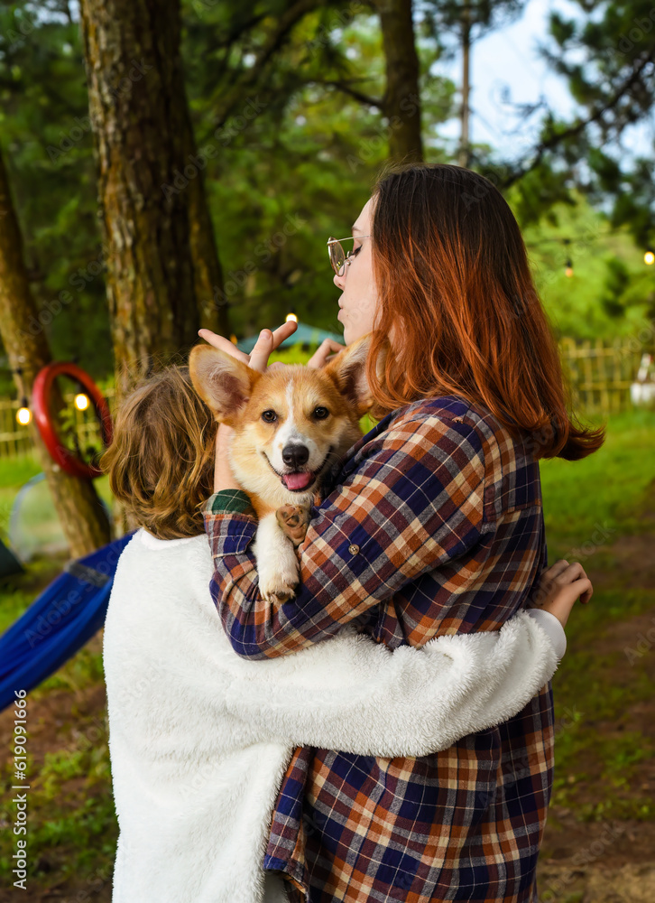 Cozy sisters holding their smiling welsh corgi dog Cozy sisters holding their smiling welsh corgi dog
