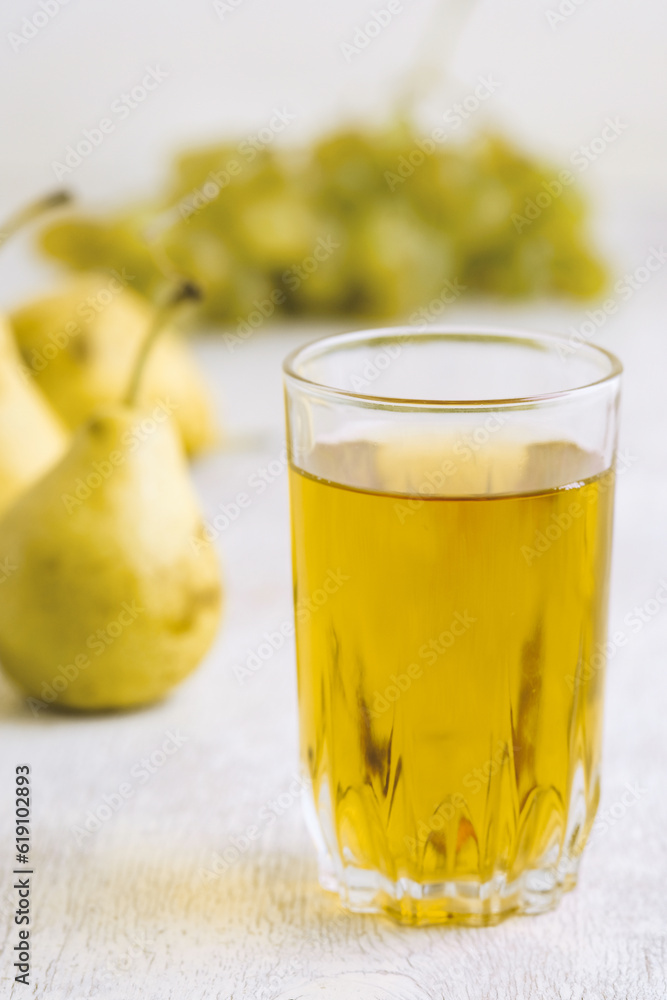 Juice of pears and grapes in a glass on a white wooden background Juice of pears and grapes in a glass on a white wooden background