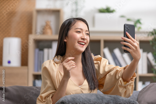 Asian young woman meeting with business team via video conference call at Home.Hand up Greetings with family group in online video call.Positive young businesswoman speaking with friends in video call