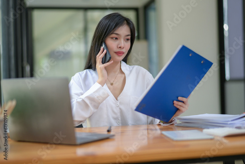 Young businesswoman working diligently, focus on working in front of the laptop. Analyze and plan new projects. Call with a colleague.