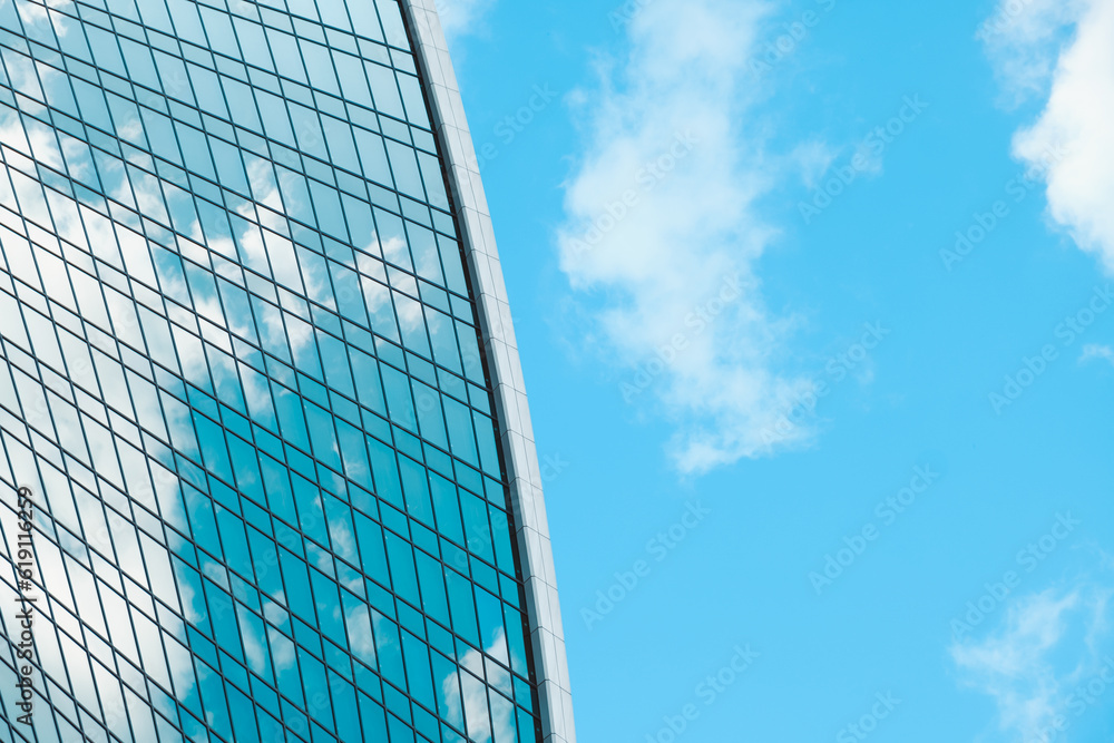View of glass facade of skyscraper and blue sky with white clouds. Modern architecture, urban space. Abstract background. View of glass facade of skyscraper and blue sky with white clouds. Modern architecture, urban space. Abstract background.
