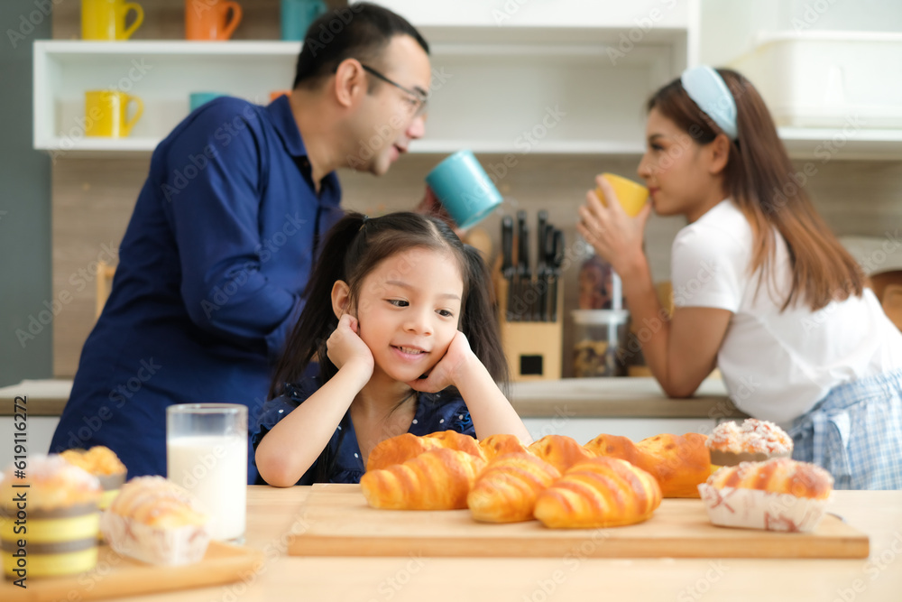 Adorable happy little child girl staring at a tray of bakery treats with mother and father holding coffee cups talking together.Family and healthy lifestyle concept.