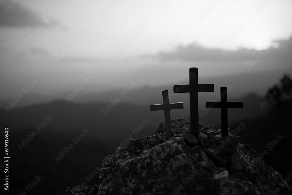 The three holy crosses of Jesus Christ shining through the red sky and clouds and bright rays background. Silhouette cross on Calvary mountain sunset background. Easter concept
