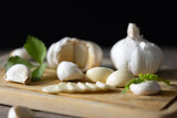 Seasoned Garlic and Herbs for Delicious Home Cooking. Fresh garlic and a variety of aromatic herbs are beautifully arranged on a wooden table, evoking the natural flavors and fragrances.