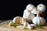Seasoned Garlic and Herbs for Delicious Home Cooking. Fresh garlic and a variety of aromatic herbs are beautifully arranged on a wooden table, evoking the natural flavors and fragrances.