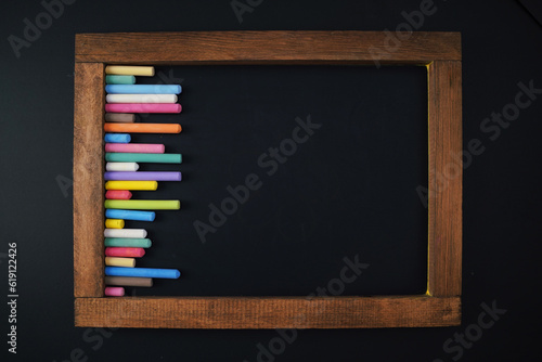 wooden frame chalkboard and colorful chalks, blank template for education and back to school design