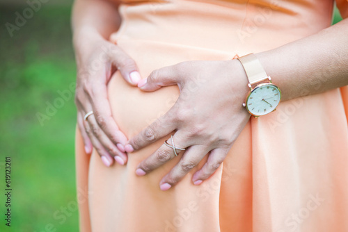 pregnant girl holding her belly with her hands in the shape of a heart