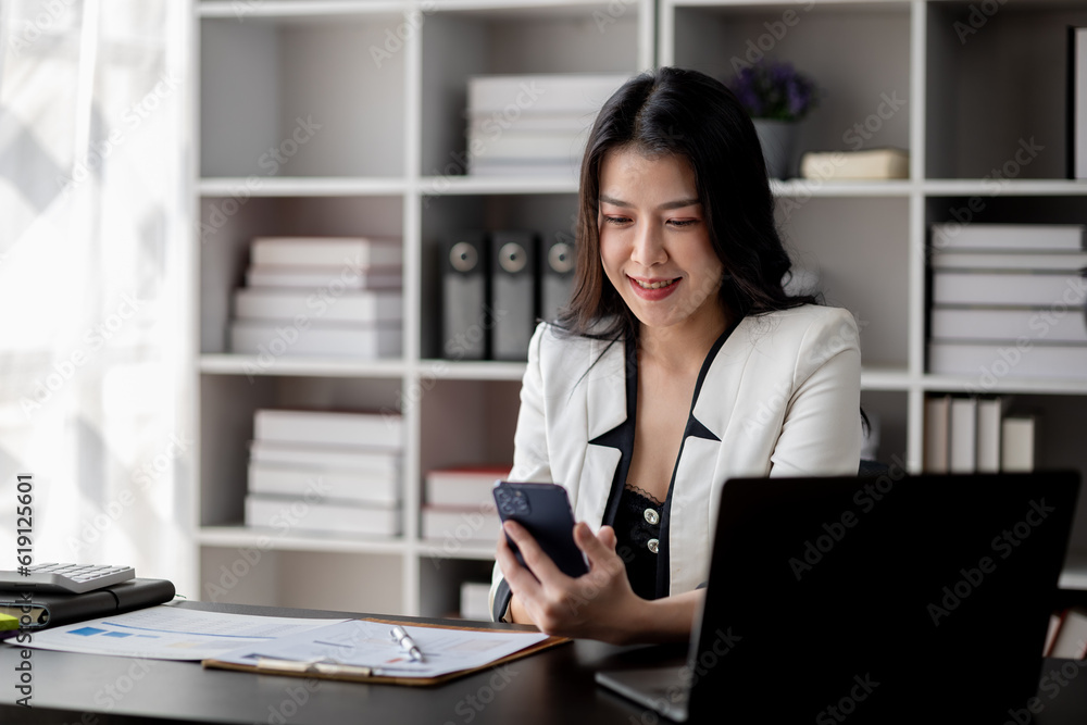 Beautiful asian woman looking at data on phone, businesswoman working in office attentively to grow and modernize start-up business, she is analyzing company's market and financial data.