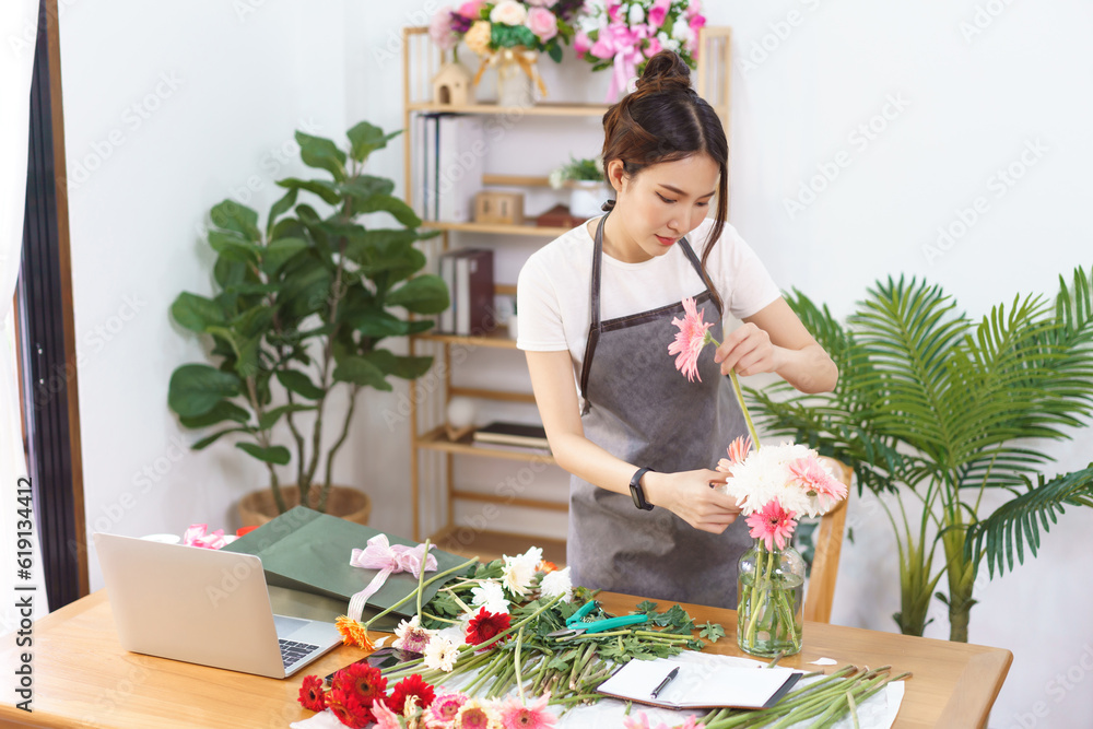 Florist concept, Female florist arranging pink gerbera and chrysanthemum in vase at flower shop Florist concept, Female florist arranging pink gerbera and chrysanthemum in vase at flower shop