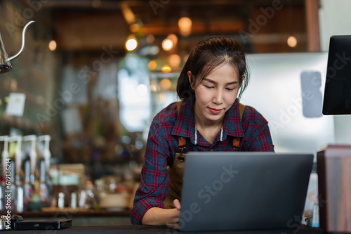 Close-up store owner smiling face when typing on laptop computer, because they are responding customer chats that come order bakery online, with cafe with lot orders, is happy with sale.